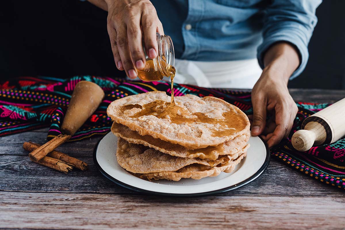 Tortillaförmige Buñuelos werden mit Anissirup beträufelt